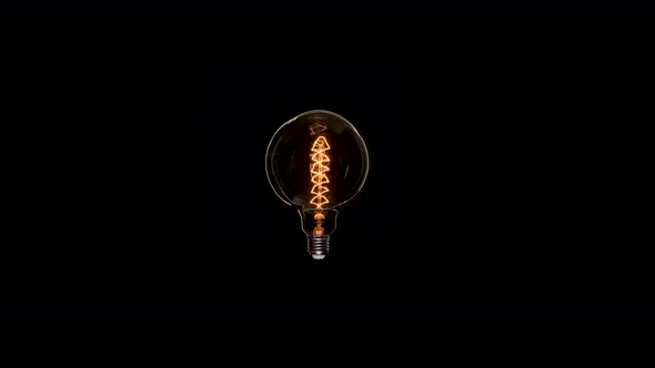 Edison Dirty Lamp with Dust Inside Glass, Flicker on Black Background. Amber Tungsten Color Old