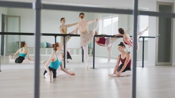 Caucasian ballet female dancers stretching up with a barre before a ballet class