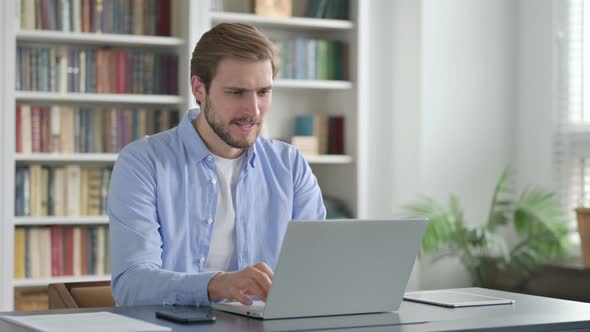 Man Celebrating While Using Laptop in Office on Bench