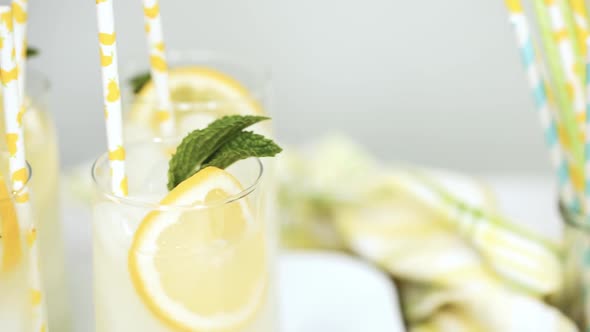 Traditional lemonade with a slice of fresh lemon and mint with paper straw in the glass.