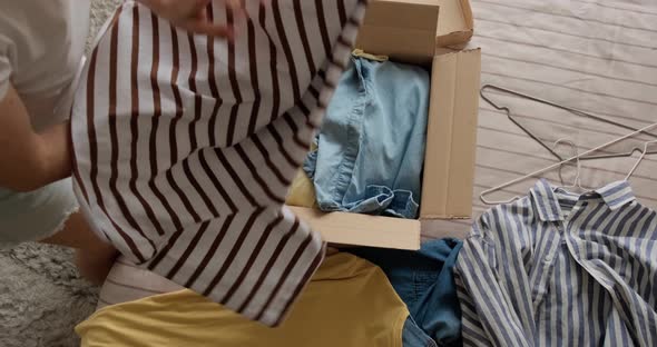 Woman packing used clothes into box to resell on the internet