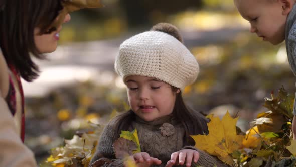 Playful Mom with Son Showering Sister with Leaves