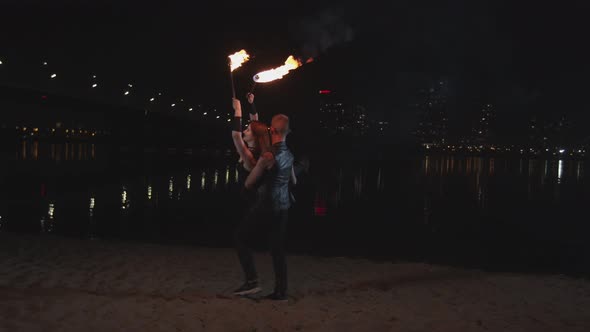 Man Holding Firegirl with Lit Torches and Spinning