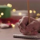 Man Writes Shopping List for Holidays in Notepad with a Pencil Under Warm Light in the Evening - VideoHive Item for Sale