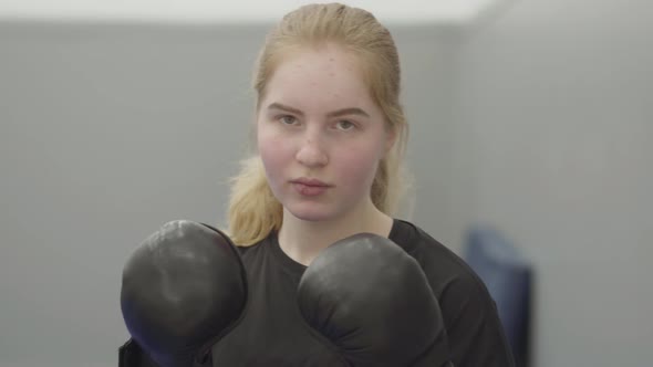 Portrait of Non-confident Blond Woman in Boxing Gloves Imitating Dodging Blows in the Gym Close Up