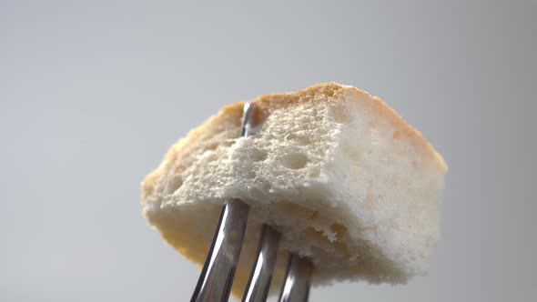 A piece of wheat bread with a crispy crust on a fork close-up. Macro