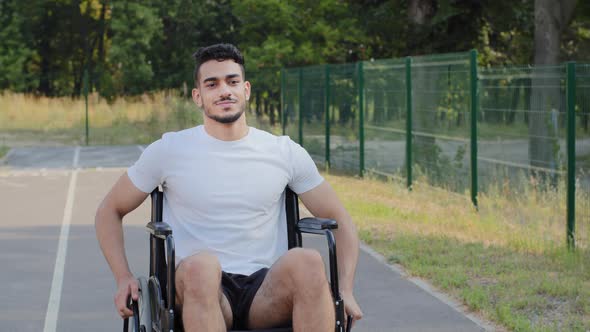 Young Middle Eastern Arabic Man Having Disability Rides Wheelchair on Summer Stadium Treadmill