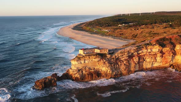 Lighthouse in Nazare Portugal near Praia do Norte during sunset, Aerial circle out shot