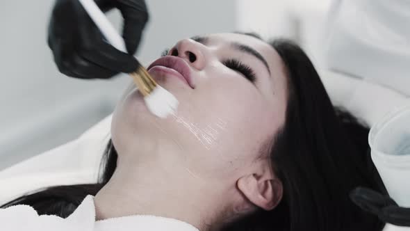 The Therapist Applies a Special Product to the Face of His Client Using a Brush