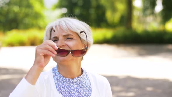 Senior Woman Taking Sunglasses Off at Summer Park 32