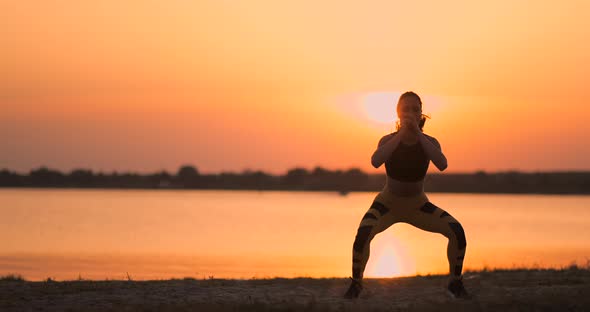 Side View of Young Woman Doing Squats Outdoors