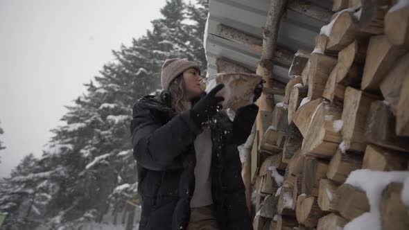 Female putting firewood in shed in winter