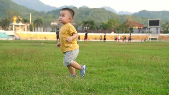 Cute Asian Toddler Boy On The Grass At Stadium