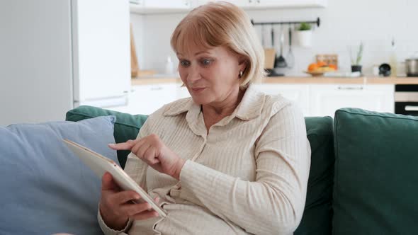 Excited Woman Sitting On Couch With Tablet Beside Herself With Joy Of Success