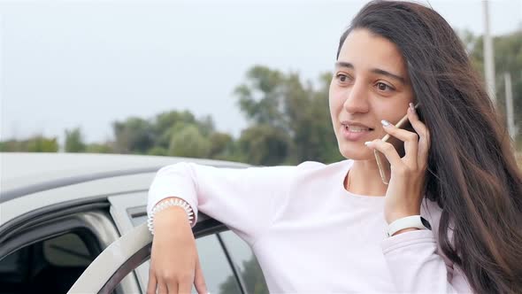 Beautiful Girl Talking on the Phone Near the Car