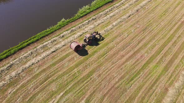 Nice Aerial View of the Tractor in the Field Collecting the Cut Grass in Bales