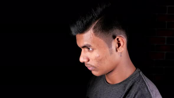 Side View of Young Man Looks His Face in a Mirror Isolated on Black