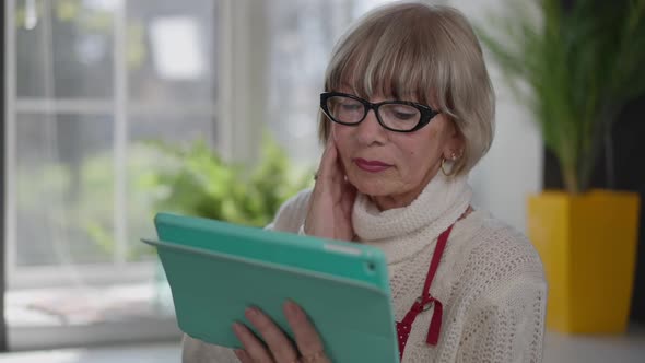 Shocked Caucasian Woman Shaking Head Reading Latest News on Tablet Standing Indoors