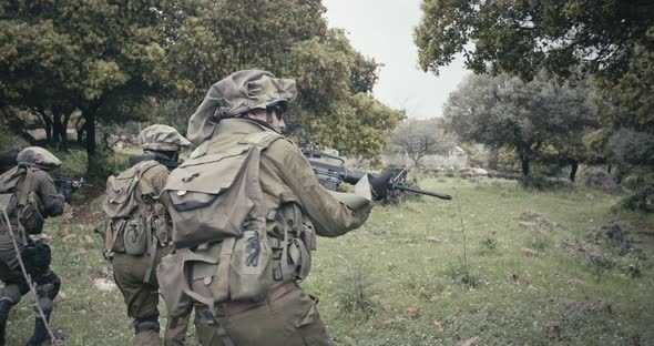 Squad of fully armed commando soldiers during combat in a forest scenery