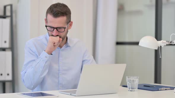 Middle Aged Man Coughing While Working on Laptop