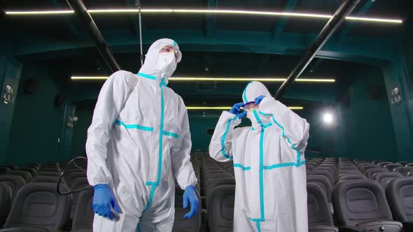 Men in Protective Suit Mask and Rubber Gloves at Cinema