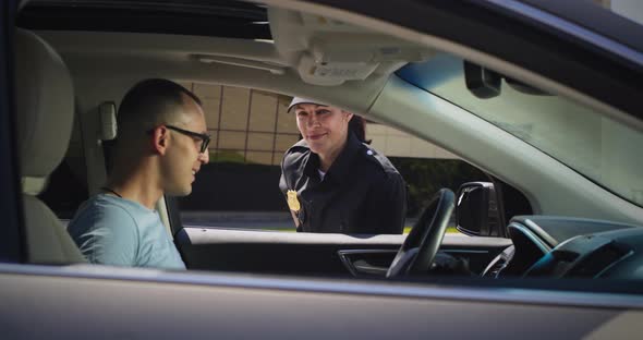 Friendly Police Officer Checking Driver License of Man