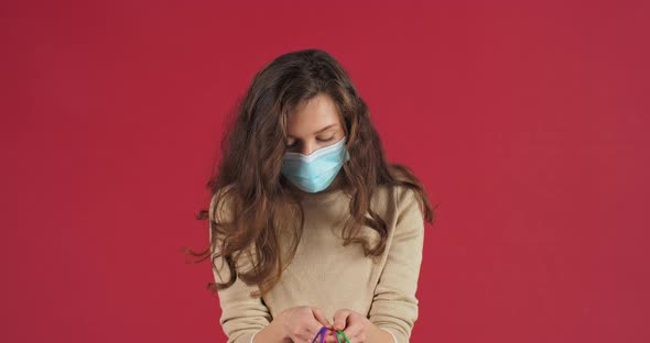 Studio Portrait Caucasian Millennial Woman Girl Model Wearing Medical Mask on Face Posing on Red