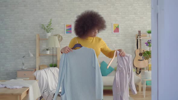 African Woman with an Afro Hairstyle Trying on Clothes in Front of a Mirror in His Modern Apartment