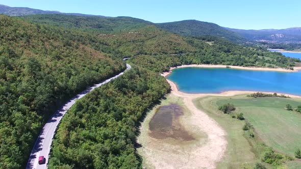 Aerial view of red van driving by artificial lake Peruca, Croatia