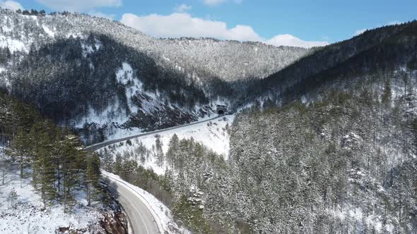 Road through the snowy mountains, going to a tunnel