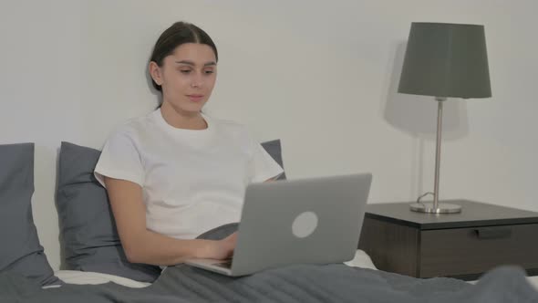 Indian Woman Smiling at Camera while using Laptop in Office