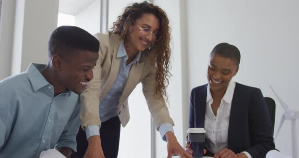 Biracial smiling female and male architects talking and checking architects plans in modern office