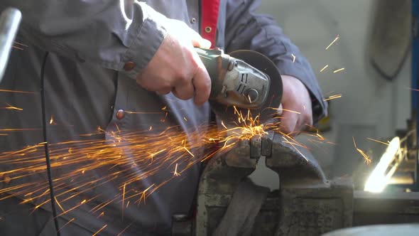 Craftsman Sawing Metal with Disk Grinder in Workshop. Man Worked Over the Steel