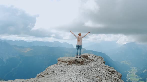 Young Woman with Outstretched Arms Enjoying the Beauty of Nature on Mountain Rock