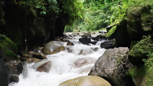 Flying over a beautiful river with large boulders sticking out the fast current 