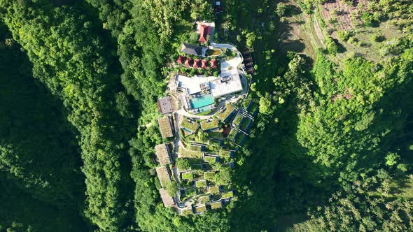 top down view of a tropical luxury pool resort villas on an island surrounded by large green hills a
