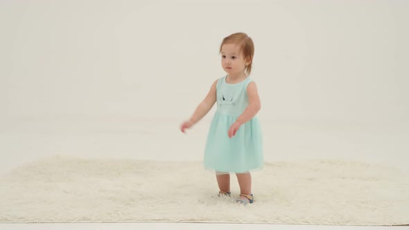 Little Girl in Dress is Playing on the Carpet