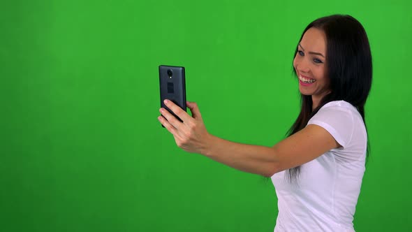 Young Pretty Woman Photographs with Smartphone (Selfie) - Green Screen - Studio