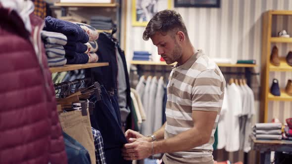 Focused Man Choosing Pants in Shop