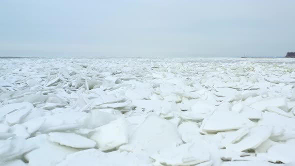 Slowly flying forward over snow covered iceburgs in lake. Tiny iceburgs in frozen lake due to wind a