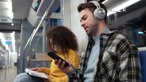 Students Go to Study in the Subway Young Man Uses a Smartphone and Listens to Music with Wireless