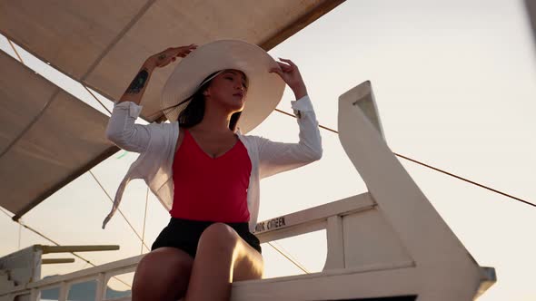 Woman Relaxing On Outrigger Boat In Sun Hat