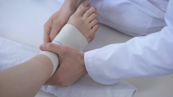 Doctor Bandaging Sprained Ankle, Running Injury After Workout, Leg Closeup