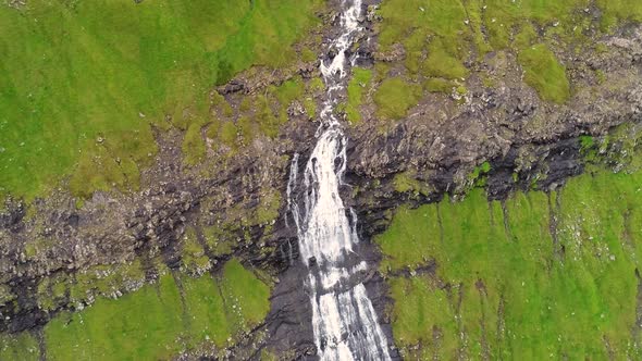 Aerial view of breathtaking waterfall crossing rock mountain, Faroe Island.