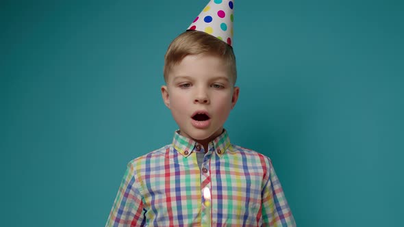 Kid in Party Hat Blowing Out Birthday Candle in Slow Motion