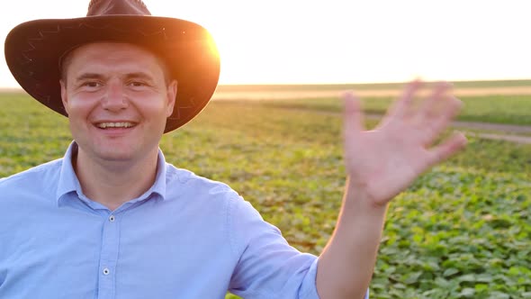 Farmer Waves His Hand at the Camera Sends Greetings in a Video Call From His Field at Sunset