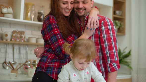 Happy Young Parents with Little Daughter Having Fun Cooking Together in Kitchen