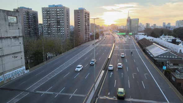 Cinematic aerial flyover La Plata Highway with traffic during golden sunset in background - Old buil