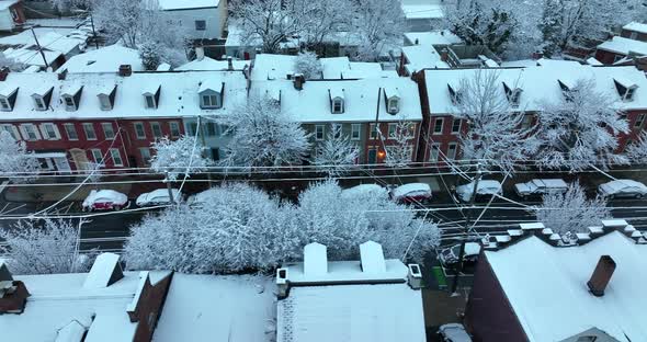 Truck shot of colorful row homes in fresh winter snow in USA. Flurries in evening. Light on. Establi