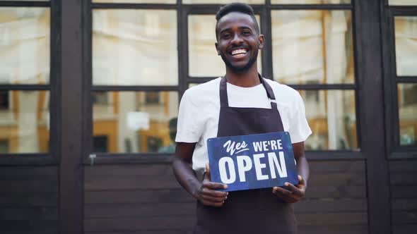 Slow Motion Portrait of Cheerful African American Businessman Cafe Owner Holding We Are Open Sign